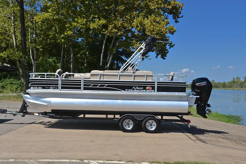 Slide: The Image of 2021 Sun Tracker Fishin Barge 20 DLX pontoon boat on trailer by a lake. - 11