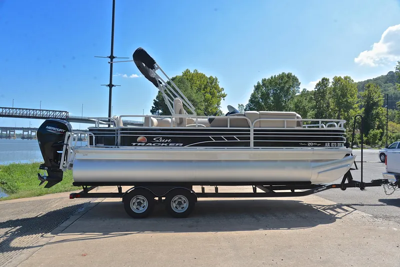 Slide: The Image of 2021 Sun Tracker Fishin Barge 20 DLX pontoon boat on trailer by a river. - 15