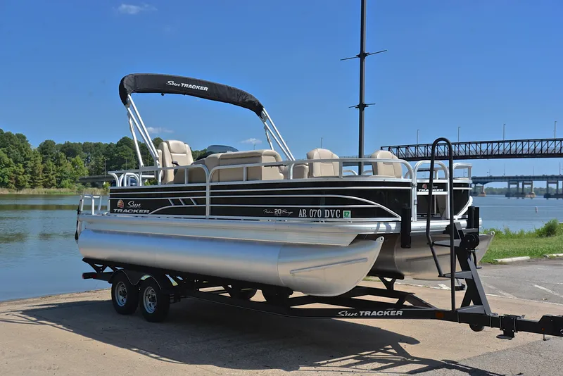 Slide: The Image of 2021 Sun Tracker Fishin Barge 20 DLX pontoon boat on trailer by a river. - 16