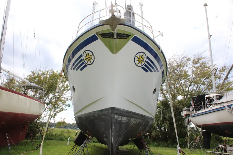 Slide: The Image of 2001 Nordhavn 40 boat on land, front view, surrounded by trees and other boats. - 18