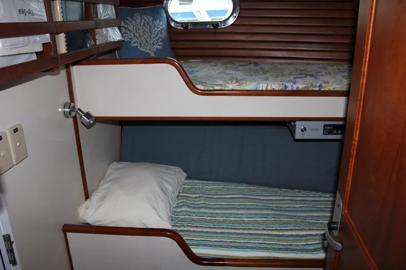 Slide: The Image of Bunk beds in 2001 Nordhavn 40 yacht cabin with wooden accents and striped bedding. - 20