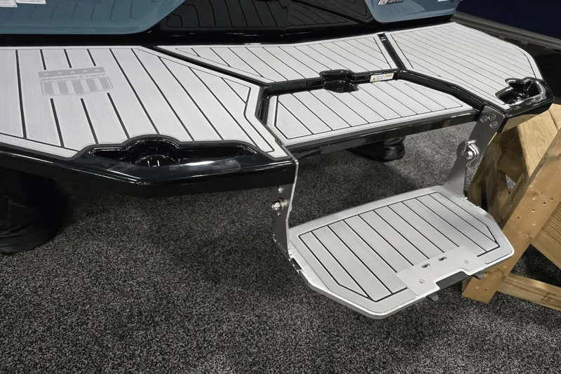 Slide: The Image of 2025 MasterCraft XT22 T boat swim platform with foldable step, displayed on carpeted floor. - 18