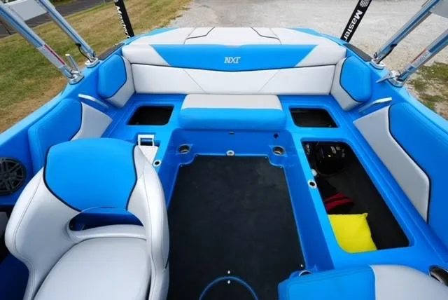 Slide: The Image of 2016 MasterCraft NXT20 boat interior with blue and white seating, open storage compartments. - 11