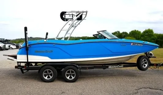 Slide: The Image of 2016 MasterCraft NXT20 boat in blue on a trailer, parked outdoors. - 4