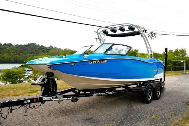Slide: The Image of 2016 MasterCraft NXT20 boat in blue on trailer, parked near a scenic lake. - 6