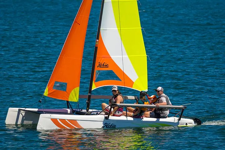 Slide: The Image of 2024 Hobie Cat Getaway sailing on blue water with colorful sails. - 3