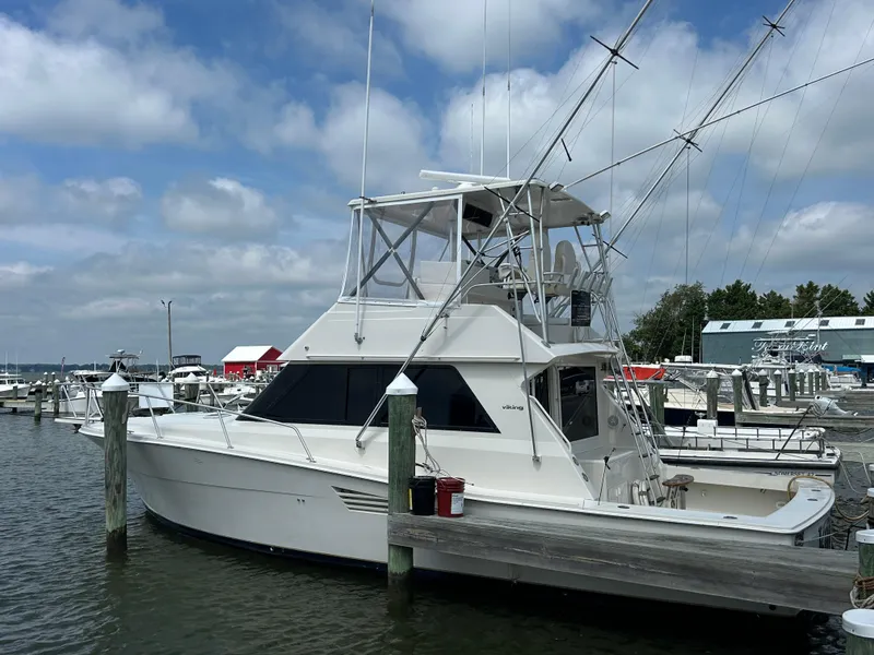 Slide: The Image of 1990 Viking 38 Convertible yacht docked at marina under cloudy sky. - 0