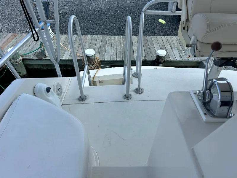 Slide: The Image of 1990 Viking 38 Convertible boat deck with controls and seating, docked at a marina. - 23