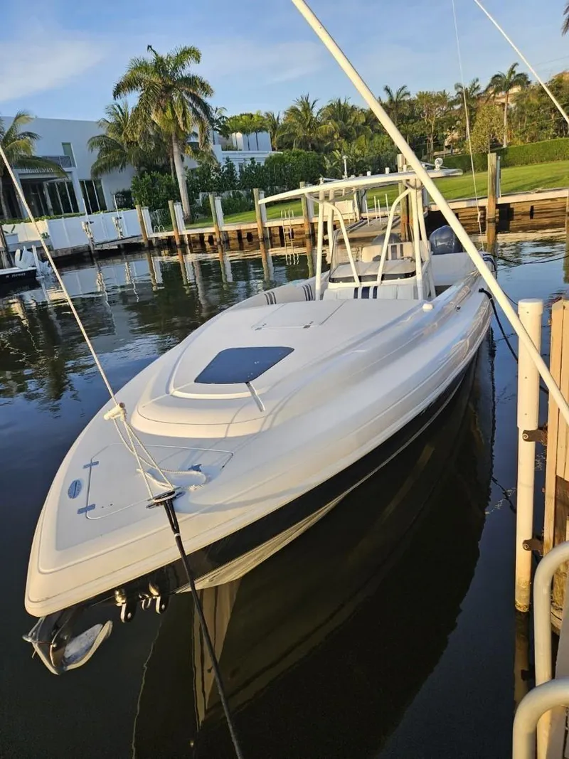 Slide: The Image of 2005 Intrepid 323 Cuddy boat docked in a serene marina setting. - 13