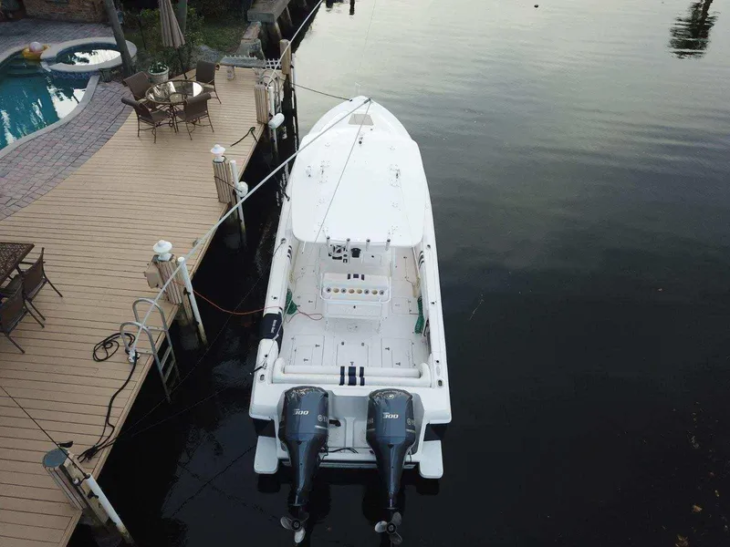 Slide: The Image of 2005 Intrepid 323 Cuddy boat docked by a wooden deck. - 15