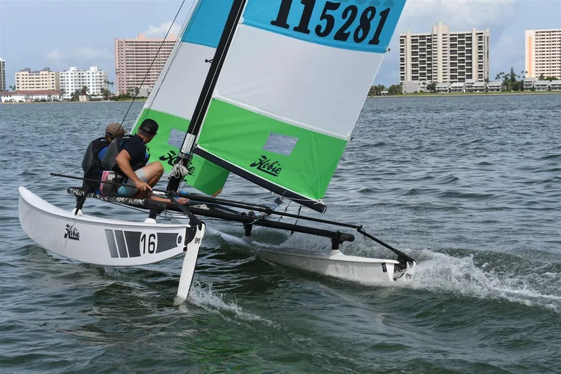 Slide: The Image of 2025 Hobie Cat 16 Catamaran sailing on water with cityscape in background. - 4