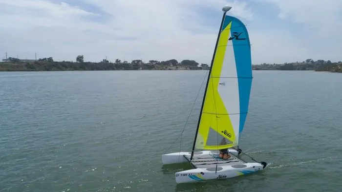 Slide: The Image of 2024 Hobie Cat Club WAVE sailing on a calm lake under a cloudy sky. - 4
