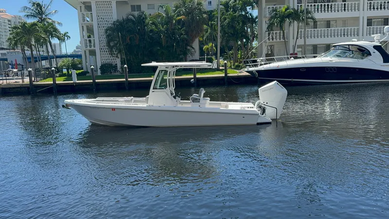 The Image of 2024 Everglades 253 Center Console boat on calm water near luxury yachts. - 0