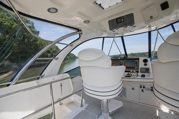 Slide: The Image of 2005 Sea Ray 500 Sedan Bridge helm with white seating and modern controls, overlooking water. - 13