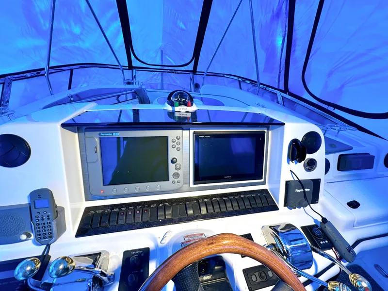 Slide: The Image of 2005 Sea Ray 500 Sedan Bridge helm with navigation screens and controls, under blue lighting. - 17
