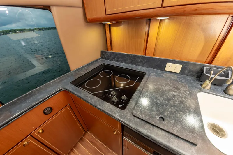 Slide: The Image of 2005 Ocean Yachts Super Sport kitchen with stovetop, sink, and wood cabinetry. - 34