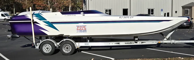 The Image of 2000 Eliminator 25 Daytona boat on trailer, white with purple and teal accents, for sale sign. - 0