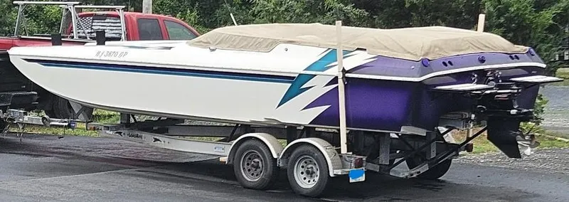 Slide: The Image of 2000 Eliminator 25 Daytona speedboat on trailer, covered, with vibrant purple and blue accents. - 11
