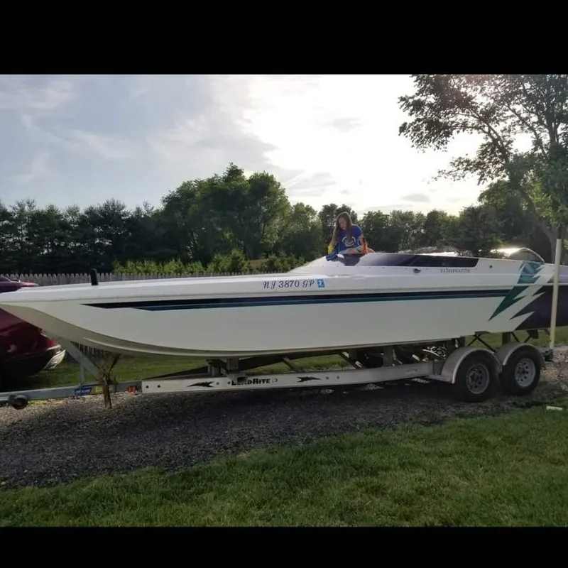 Slide: The Image of 2000 Eliminator 25 Daytona boat on trailer, parked outdoors with trees in background. - 17