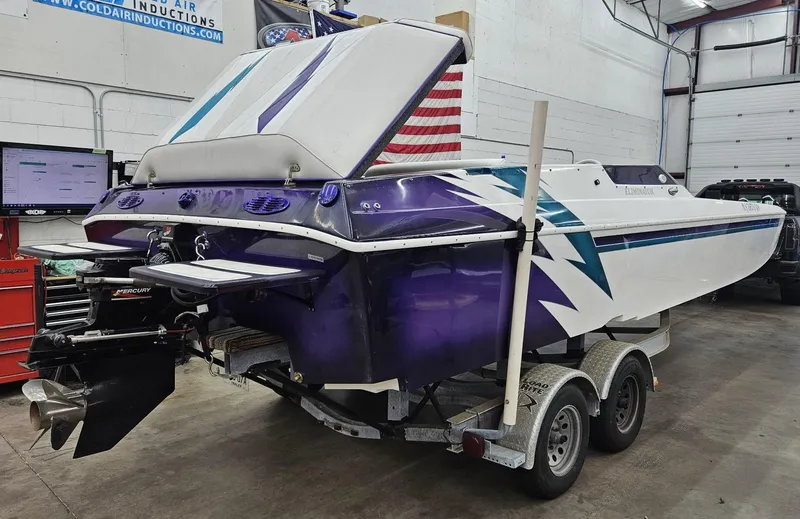 Slide: The Image of 2000 Eliminator 25 Daytona speedboat with vibrant purple and white design on a trailer in a garage. - 2