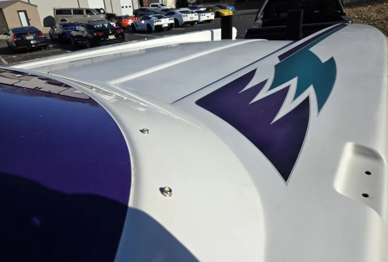 Slide: The Image of 2000 Eliminator 25 Daytona boat with vibrant graphics, parked near various vehicles. - 22