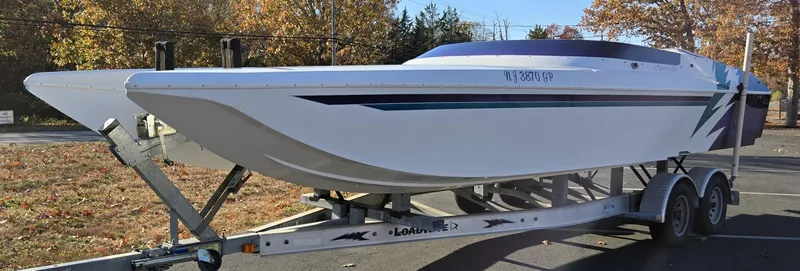 Slide: The Image of 2000 Eliminator 25 Daytona boat on trailer, parked outdoors in autumn setting. - 23