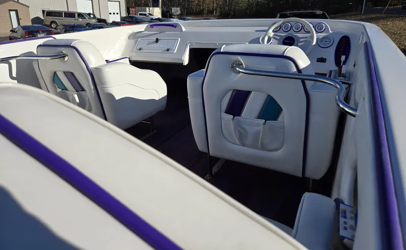 Slide: The Image of 2000 Eliminator 25 Daytona boat interior with white and purple seating, dashboard, and controls. - 26