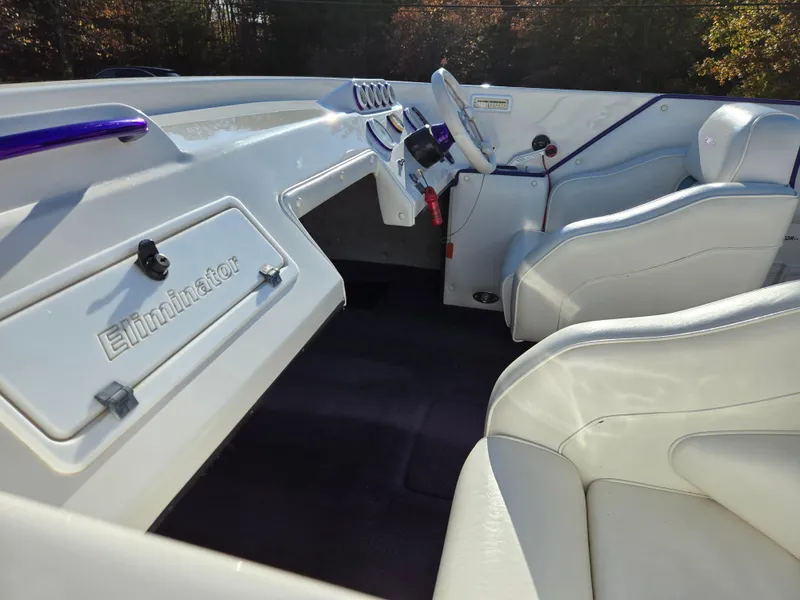 Slide: The Image of Interior of a 2000 Eliminator 25 Daytona boat with white seating and dashboard. - 9