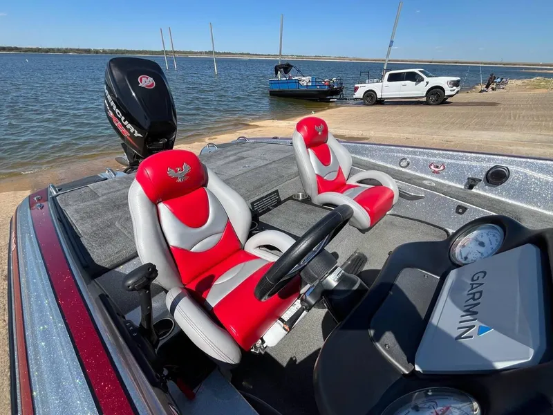 Slide: The Image of 2015 Phoenix 819 Pro boat with red seats, Garmin system, and Mercury engine by a lake. - 11