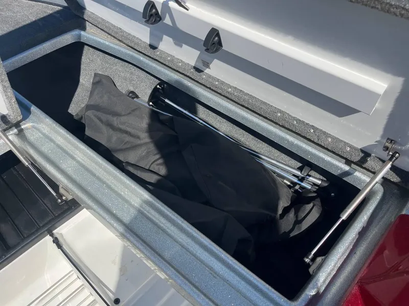 Slide: The Image of Open storage compartment in 2015 Phoenix 819 Pro boat, containing black cover and metal rods. - 15