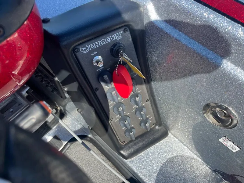 Slide: The Image of Control panel of a 2015 Phoenix 819 Pro boat with switches and key. - 24