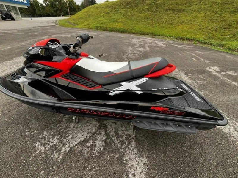 Slide: The Image of 2011 Sea-Doo RXP 255 jet ski, black and red, parked on pavement. - 11