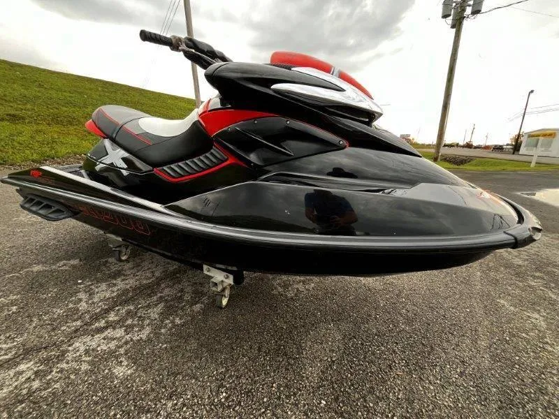 Slide: The Image of 2011 Sea-Doo RXP 255 jet ski, black and red, parked on pavement. - 13