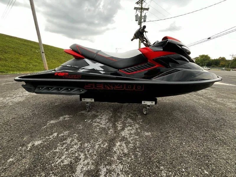 Slide: The Image of 2011 Sea-Doo RXP 255 jet ski, black and red, parked on asphalt. - 14
