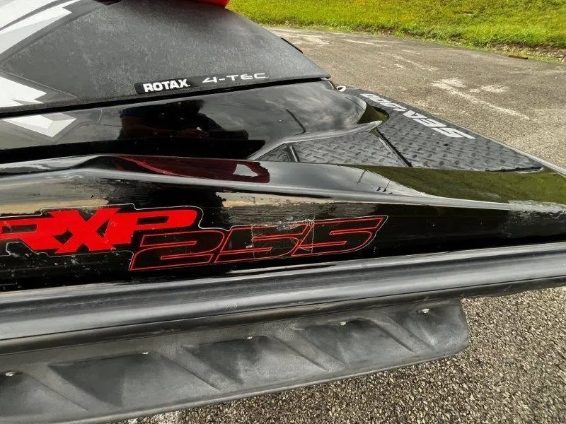 Slide: The Image of 2011 Sea-Doo RXP 255 jet ski, black with red decals, parked on pavement. - 20