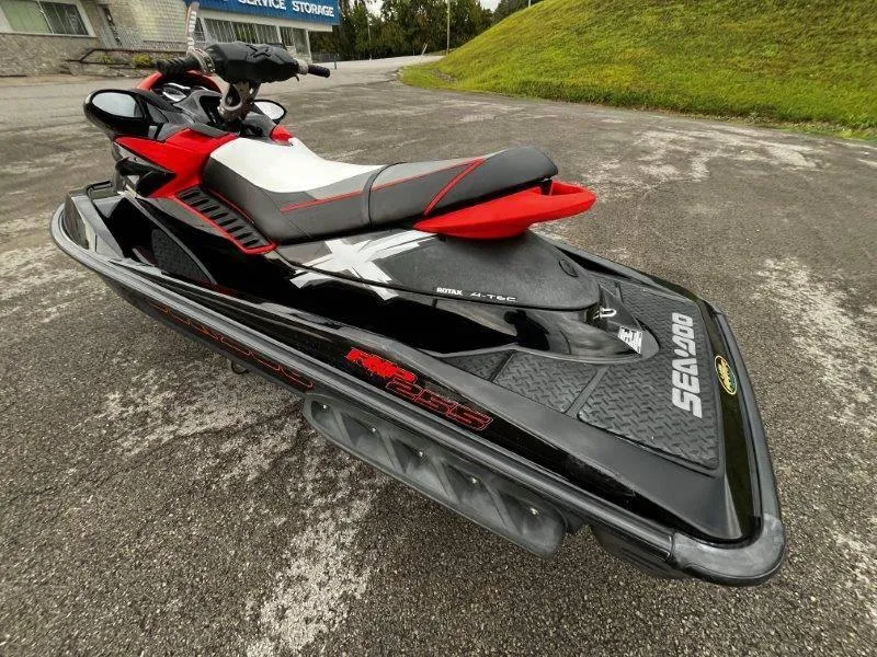 Slide: The Image of 2011 Sea-Doo RXP 255 jet ski, black and red, parked on pavement. - 23