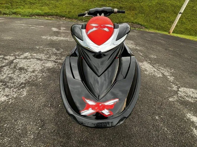 Slide: The Image of 2011 Sea-Doo RXP 255 jet ski, black and red, parked on asphalt. - 3