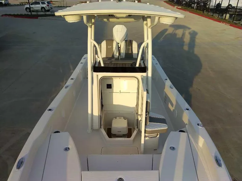 Slide: The Image of 2024 Ranger 2510 Bay boat with center console and T-top in a parking area. - 10