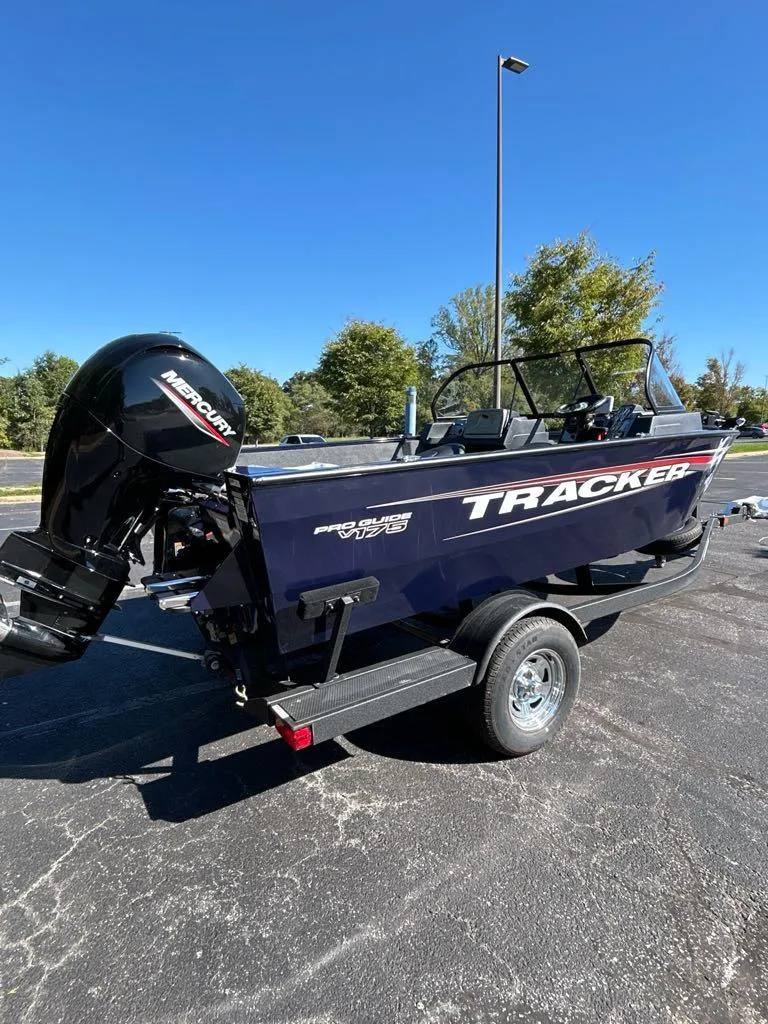 Slide: The Image of 2025 Tracker Pro Guide V-175 Combo boat on trailer, outdoors under clear blue sky. - 2