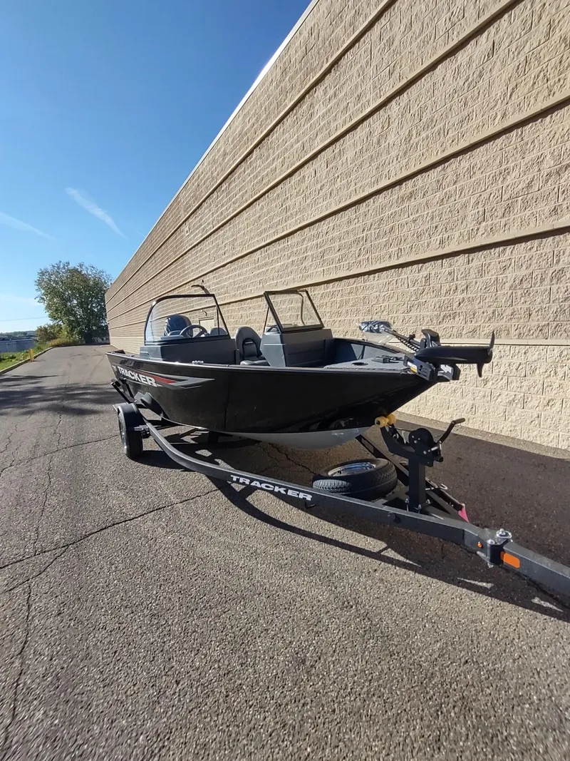 Slide: The Image of 2025 Tracker Pro Guide V-175 WT boat on trailer, parked beside a brick wall. - 3