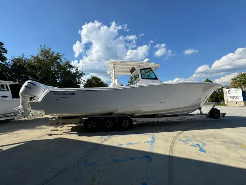 Slide: The Image of 2025 Caymas 401 CC boat on trailer under a clear blue sky. - 13