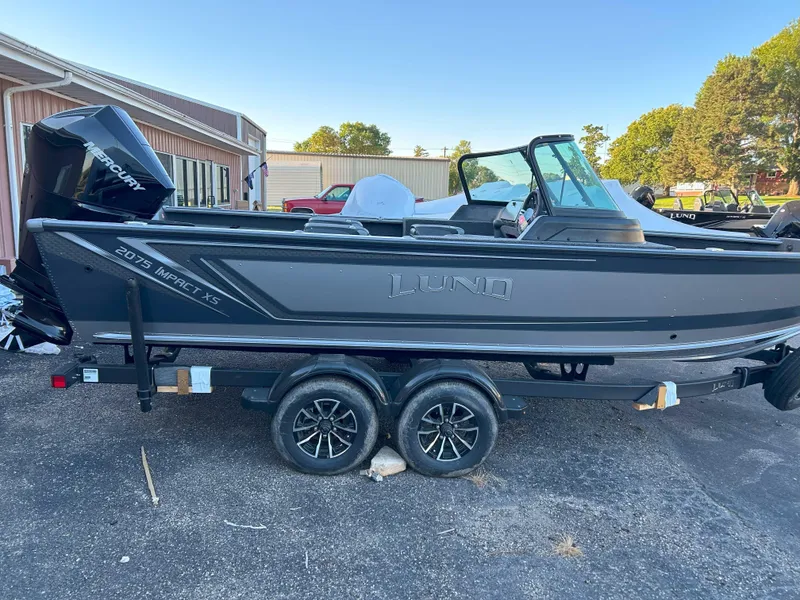 Slide: The Image of 2025 Lund 2075 Impact XS fishing boat on trailer, parked outdoors. - 2