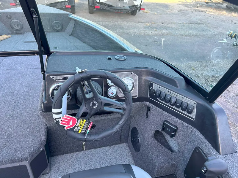 Slide: The Image of 2025 Lund 2075 Impact XS Fishing Boat dashboard with steering wheel and controls. - 4