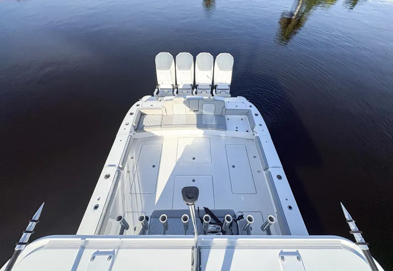 Slide: The Image of 2023 HCB 53 Sueños boat deck with seating and rod holders on calm water. - 18
