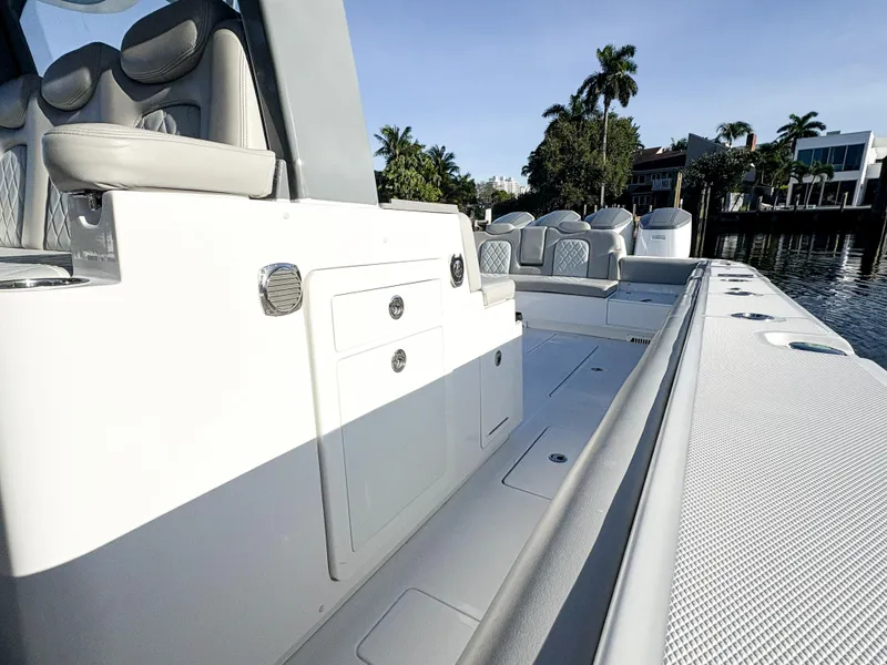 Slide: The Image of 2023 HCB 53 Sueños luxury boat interior with sleek seating and storage, docked by palm trees. - 19