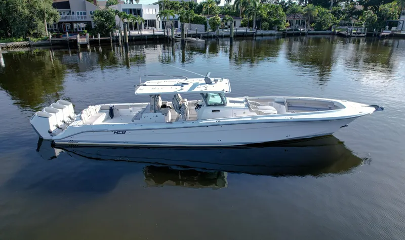 Slide: The Image of 2023 HCB 53 Sueños luxury boat on calm water, surrounded by lush greenery. - 2