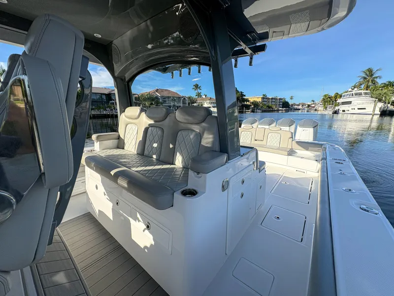 Slide: The Image of 2023 HCB 53 Sueños luxury boat interior with plush seating, docked by waterfront homes. - 29