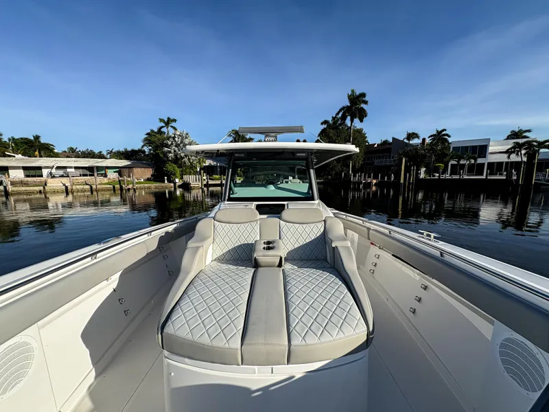 Slide: The Image of 2023 HCB 53 Sueños luxury boat with elegant seating, docked by waterfront homes. - 39