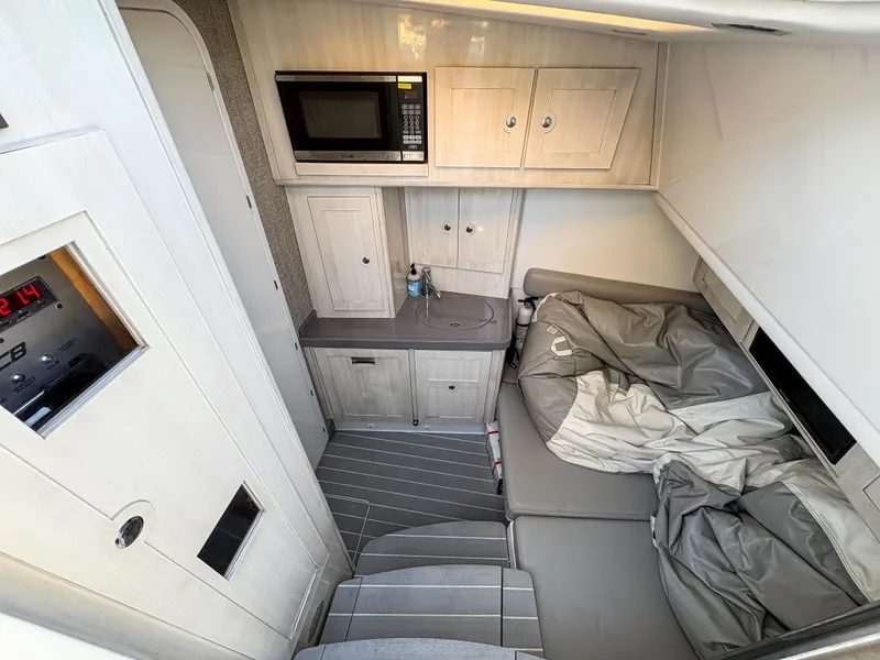 Slide: The Image of 2023 HCB 53 Sueños cabin interior with bed, microwave, and storage cabinets. - 43