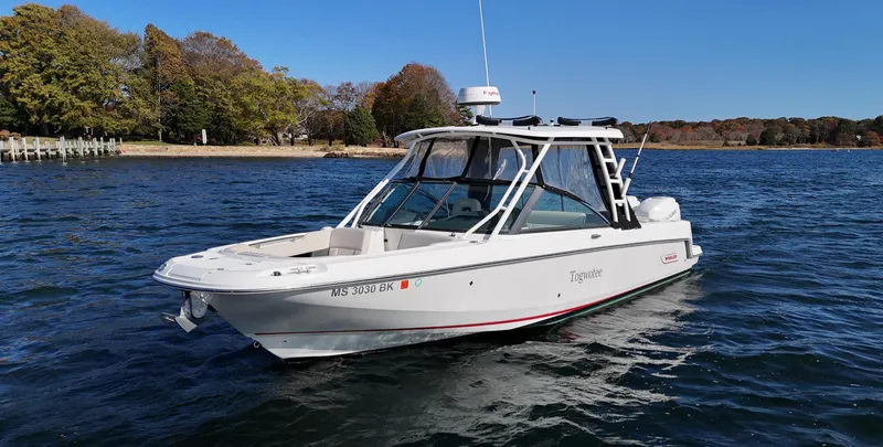 The Image of 2018 Boston Whaler 270 Vantage boat on calm water near a wooded shoreline. - 0